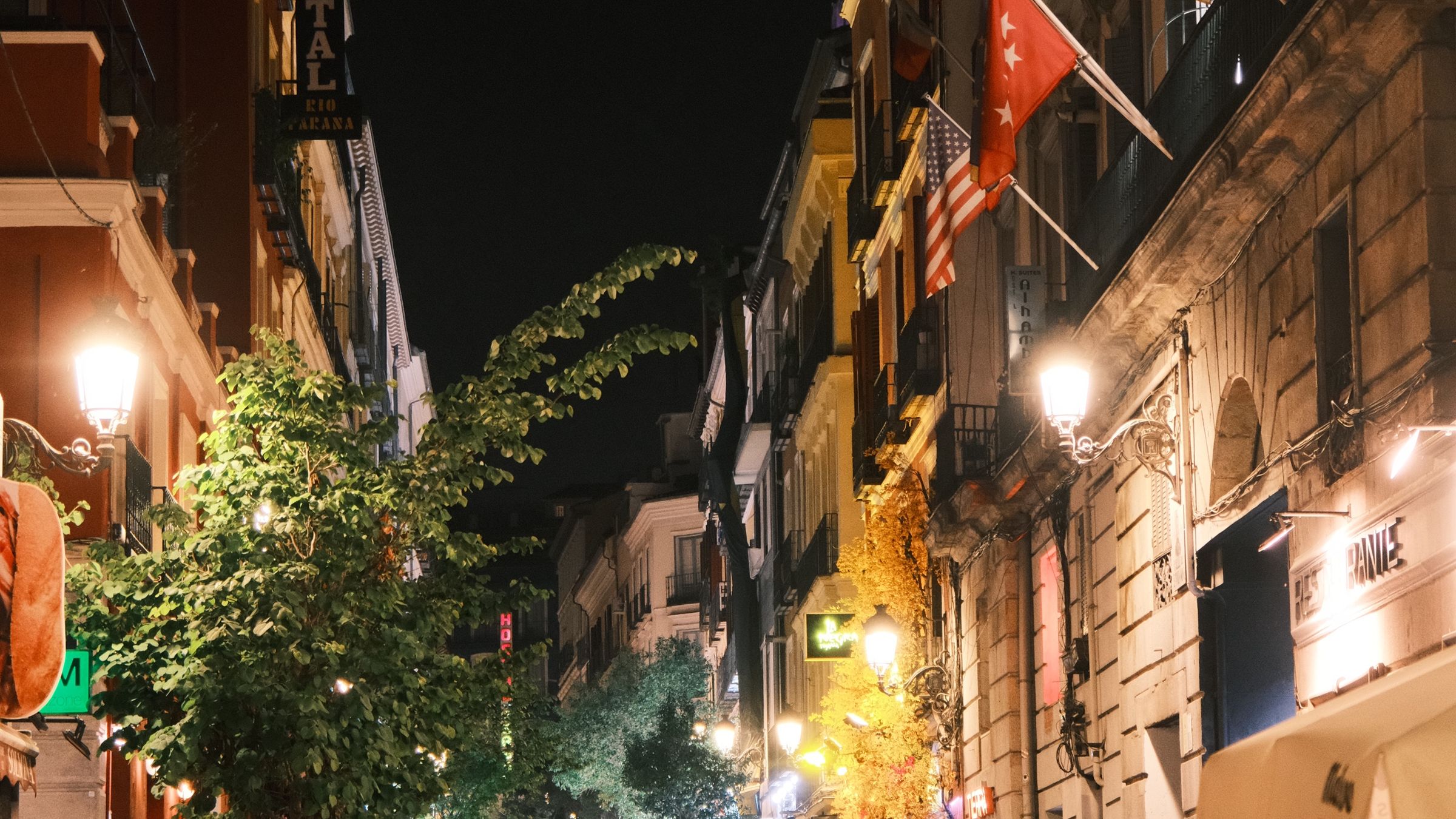 Crowded pedestrian street at night lined with open-fronted bars and lit signs