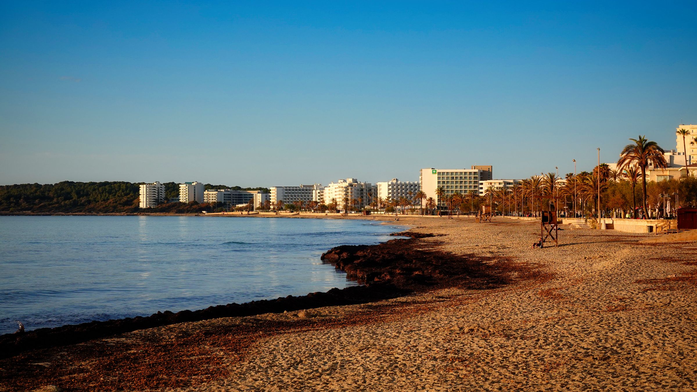 Row of white resort hotel blocks standing behind a Mediterranean beach