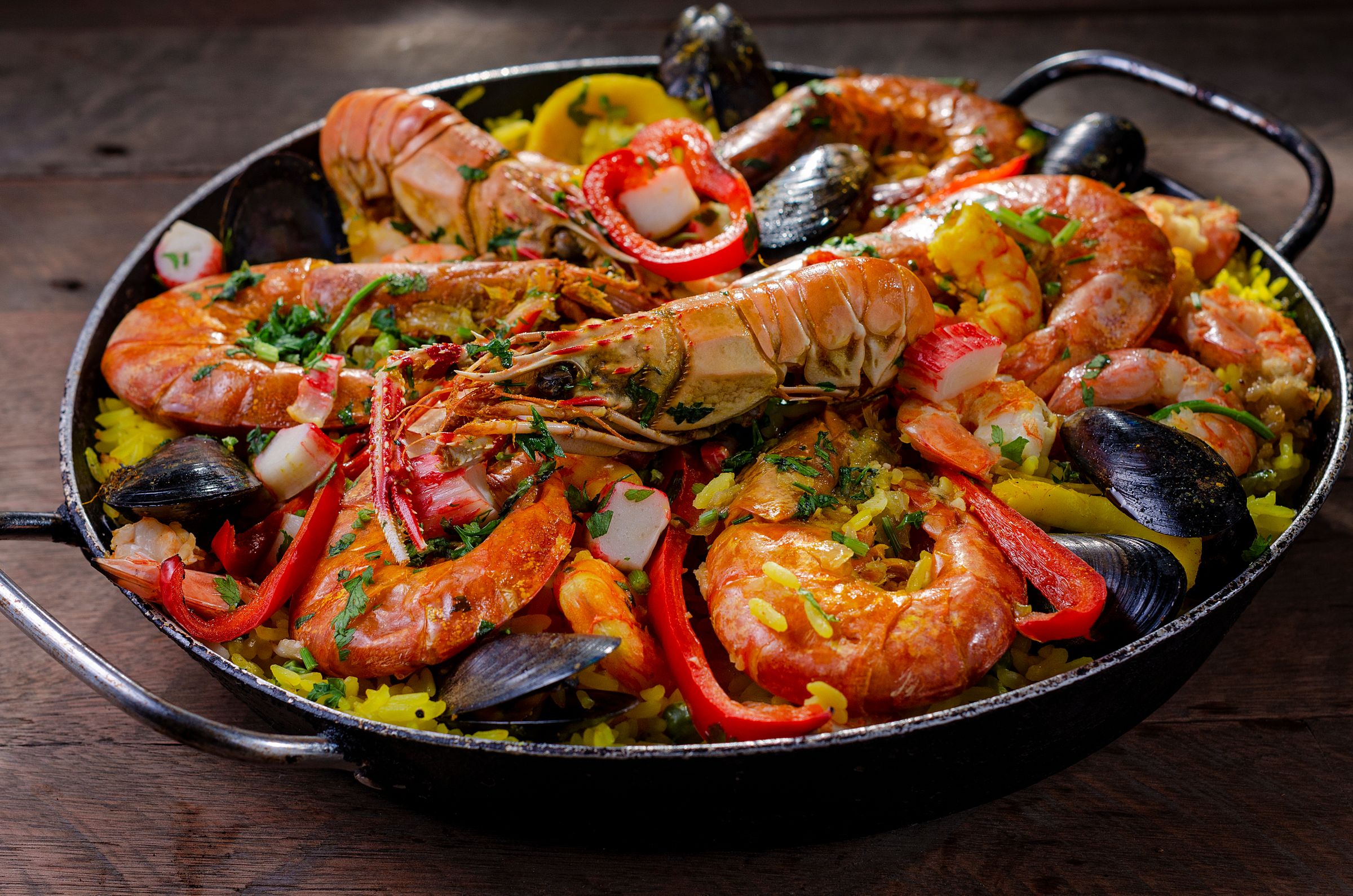 Seafood paella in a pan with langoustines, prawns and mussels over saffron rice